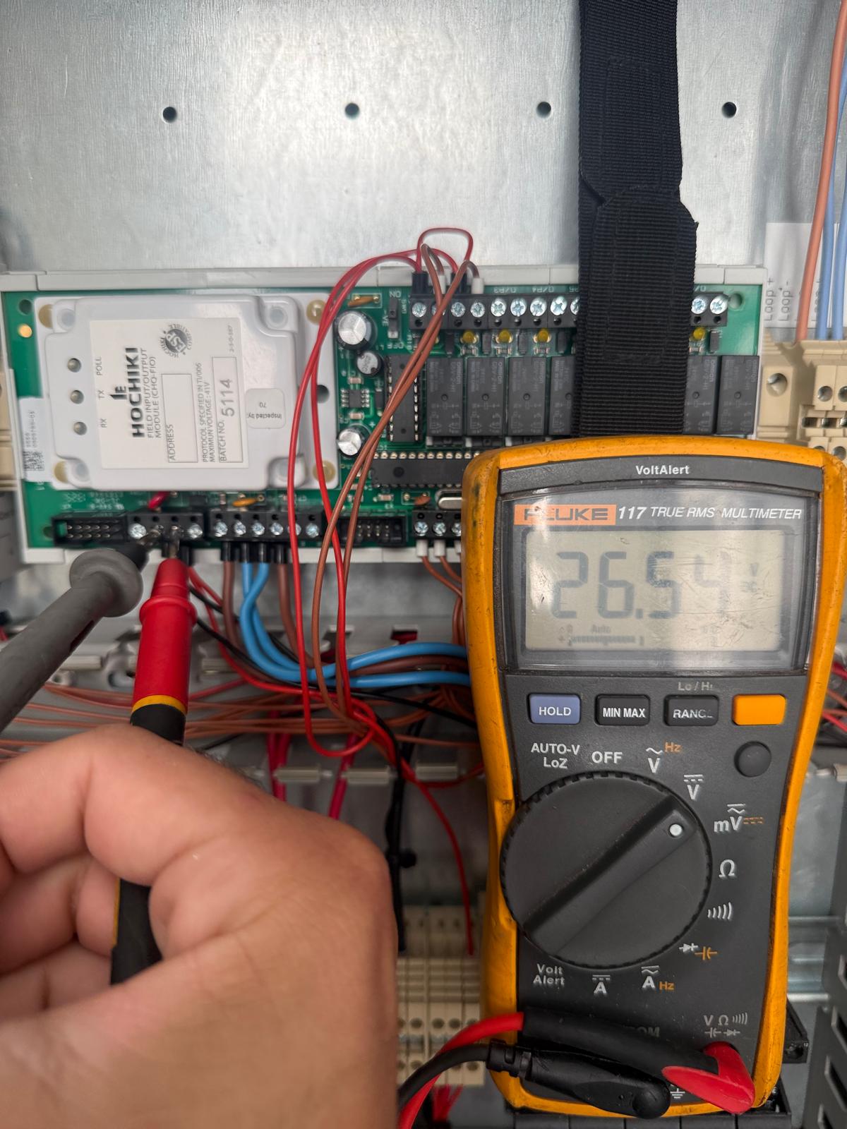 Electrical testing inside a mechanical AOV fan control panel during remedial work in East London
